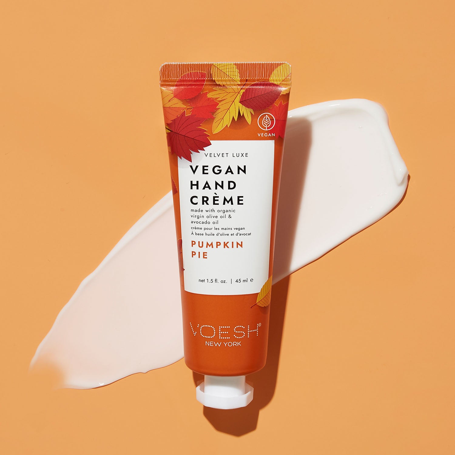 Pumpkin Pie Vegan Hand Crème on top of lotion’s texture on an orange background.